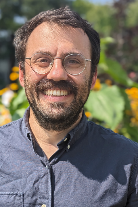 Alex headshot outside with flowers and foliage behind