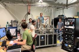 Five people work in a lab full of computers and other equipment